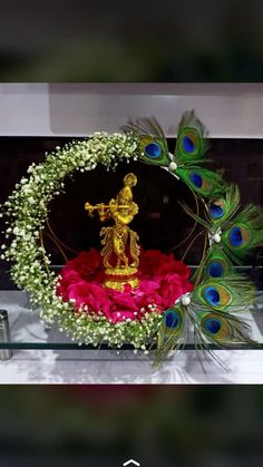 a peacock statue sitting on top of a table next to a wreath with flowers and leaves