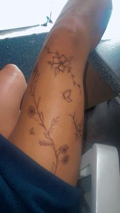 a woman's legs with tattoos on them and flowers in the middle of her leg