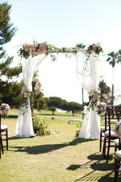 an outdoor wedding setup with white drapes and pink flowers