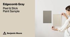 a woman is painting a wall with gray paint and she has her hands on the white panel