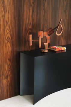 a black table with an umbrella on it next to a wall mounted lamp and books