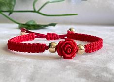 a red bracelet with gold beads and a rose on it