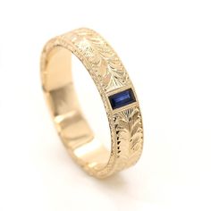 a gold ring with a blue stone in the center and engraving on it's side