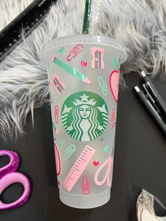 the starbucks cup is decorated with pink, green and white designs on it's side