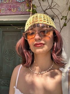 a woman with pink hair and glasses wearing a yellow hat on top of her head