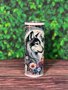 a stainless steel tumbler with an image of a wolf and flowers on the side