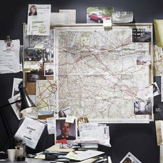 a map is hanging on the wall next to a desk with papers and other items