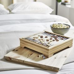 a wooden board game sitting on top of a bed next to a bowl of popcorn