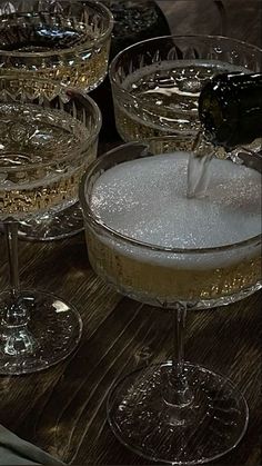 champagne being poured into wine glasses on a table