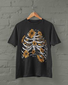 Skeleton ribs and sunflowers T Shirt Printed on a super soft, cotton tee Dispatched in 5 working days or sooner Unisex Free UK delivery Material: 100% ringspun cotton. Chest (to fit): S  34/36   M  38   L  40/42   XL  44/46   XXL  48/50 ECO-FRIENDLY Each garment is made to order, reducing extra material and energy that would be otherwise wasted We use DTG printing process which is easier on the environment than screen-printing Our ink is bright and also eco-friendly. Do not tumble dry. Wash at 3 Dark Academia Tops, Academia Tops, Skeleton Ribs, Fairycore Dark Academia, Witchy Clothes, Witchy Clothing, Fairycore Dark, Grunge Fairycore, Sunflower Shirt