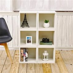 a black chair sitting on top of a wooden floor next to a shelf filled with books