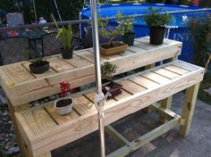 a wooden table with an umbrella and potted plants on it