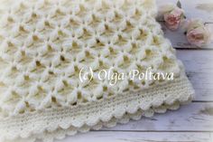 a white crocheted blanket sitting on top of a wooden table next to flowers