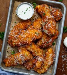 chicken wings covered in parmesan cheese and parsley with ranch dressing on the side