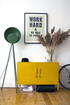 a yellow cabinet sitting on top of a hard wood floor next to a green lamp