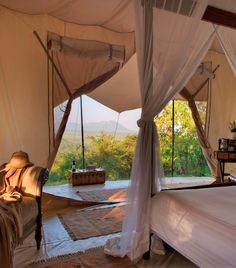 a bed sitting inside of a tent next to a window