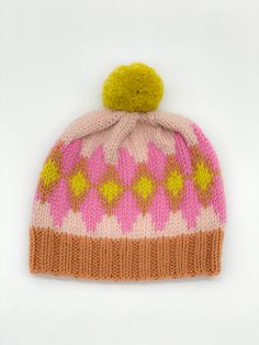 a pink and yellow knitted hat with pom - pom