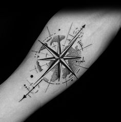 a black and white compass tattoo on the left inner arm, with arrows in it