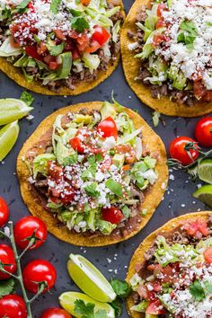 mexican food with tomatoes, lettuce and other toppings on a black surface