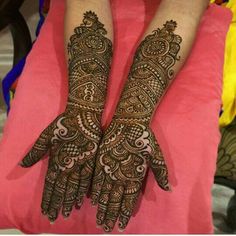 two hands with henna tattoos on them, one is showing the intricate pattern and the other has an elaborate design