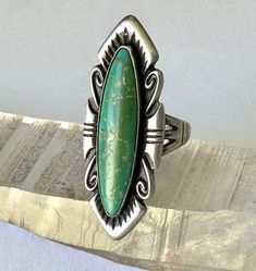 a vintage southwestern trading post ring, tall!  this is made in sterling with green turquoise, quite green.  there are some pits in the stone, hard to tell if they are natural or not.  the ring has reasonable wear, wonderful design. size:  5.25 height of face:  just under 1 and 9/16" width of inner band:  1/8" Green Turquoise Ring With Patina In Sterling Silver, Vintage Green Turquoise Ring Stamped 925, Vintage Green Turquoise Ring With Inlay, Southwestern Style Collectible Turquoise Ring, Southwestern Style Green Turquoise Collectible Ring, Western Green Turquoise Ring In Sterling Silver, Southwestern Green Oval Turquoise Ring, Collectible Green Turquoise Bohemian Ring, Collectible Bohemian Green Turquoise Ring