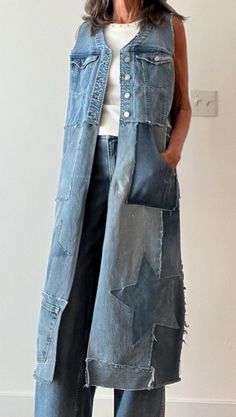 a woman standing in front of a white wall wearing a jean vest with pockets and buttons