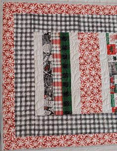 a quilted table runner with red and white checkered fabric on the border,