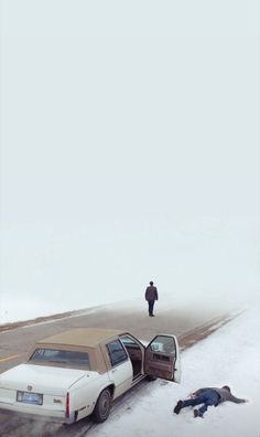 a car that is sitting in the snow next to a person laying on the ground