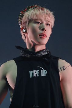 a man with blonde hair and piercings wearing a black tank top that says hype up