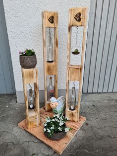 three wooden shelves with plants and flowers in them on a wood platform outside the building