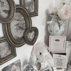 a white teddy bear sitting on top of a table next to framed pictures and flowers