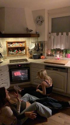 three women sitting on the floor in front of an oven