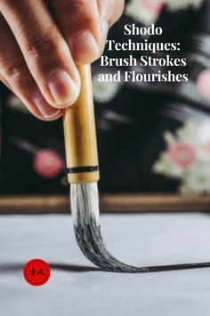 a person holding a paintbrush with the words shodo techniques brush strokes and flourishes