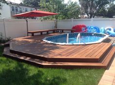 an above ground pool surrounded by wooden decking and inflatable water sliders