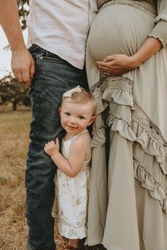 a baby girl standing next to her parents belly