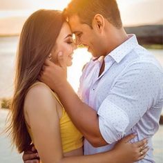 a man and woman embracing each other in front of the ocean at sunset or sunrise