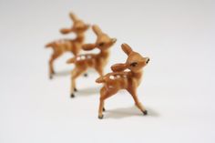 three tiny deer figurines are shown on a white surface