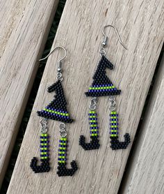 three pieces of black and green beaded earrings sitting on top of a wooden table