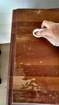 a person cleaning a wooden table with a rag