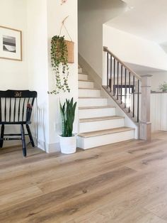 there is a chair next to the stairs in this living room with wood flooring