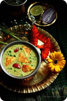 there is a bowl of soup on the table with flowers and other items around it