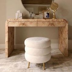 a white stool sitting under a mirror next to a wooden table with a round mirror on it