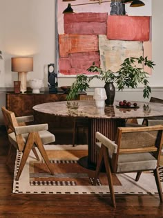 a dining room table with two chairs and a painting on the wall behind it,