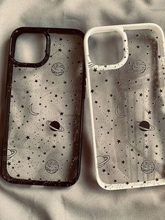 two iphone cases sitting on top of a bed covered in white and black stars,