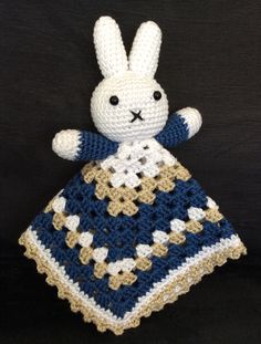 a crocheted stuffed animal sitting on top of a black table next to a white and blue blanket