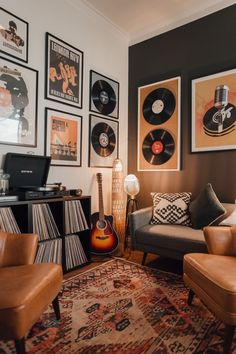 a living room filled with furniture and lots of records on the wall next to a guitar