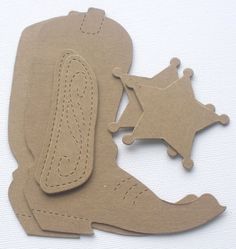 a pair of cowboy boots and a star cut out of cardboard on a white surface