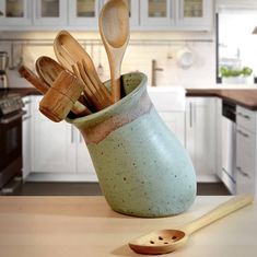 wooden spoons and utensils in a ceramic cup on a kitchen countertop