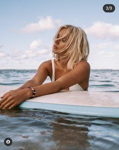 a woman sitting on top of a surfboard in the ocean with her arms crossed