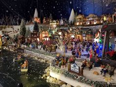 a christmas village with lots of people and boats in the water, lights on trees and buildings